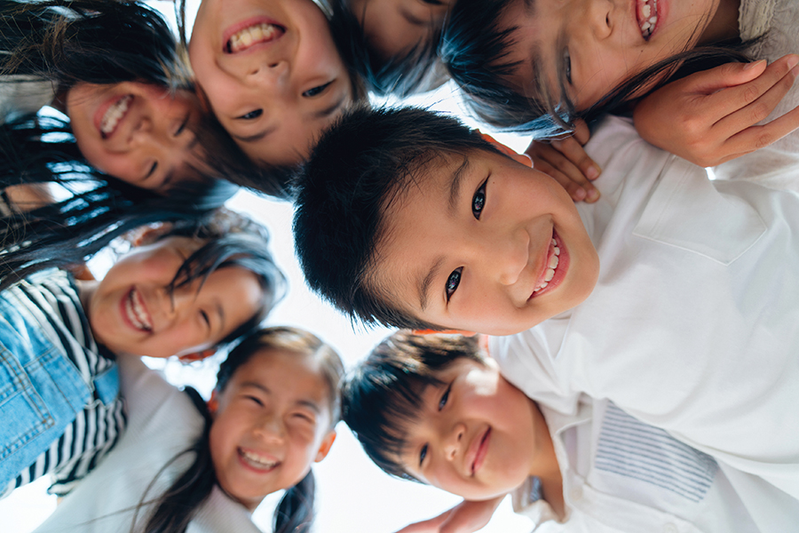 Diverse Asian children looking down at camera in circle formation, representing the next generation of civic engagement